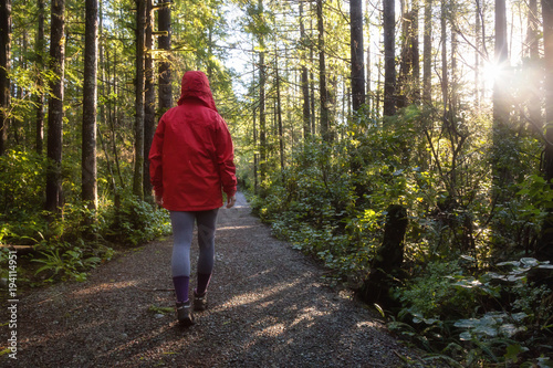 Girl wearing a bright red jacket is walking the the beautiful woods during a vibrant winter morning. Taken in Ucluelet, Vancouver Island, BC, Canada. © edb3_16