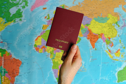 red passport on the world map in women's hands