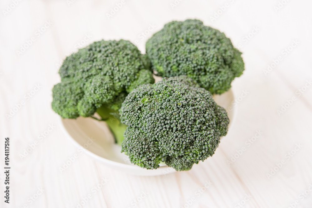 raw broccoli in the white plate.wooden table.minimalist style.top view raw broccoli in the white plate.wooden table.minimalist style.top view