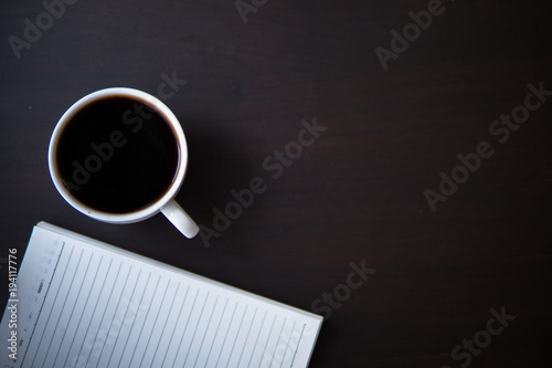 single coffee cup with notebook on wood table