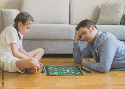 Little girl and her father playing scrabble board game. photo