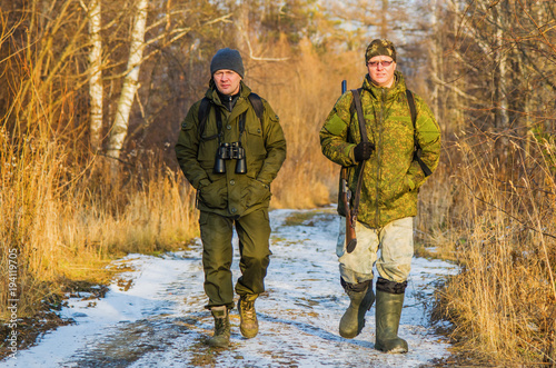 Two hunters in the forest in late autumn