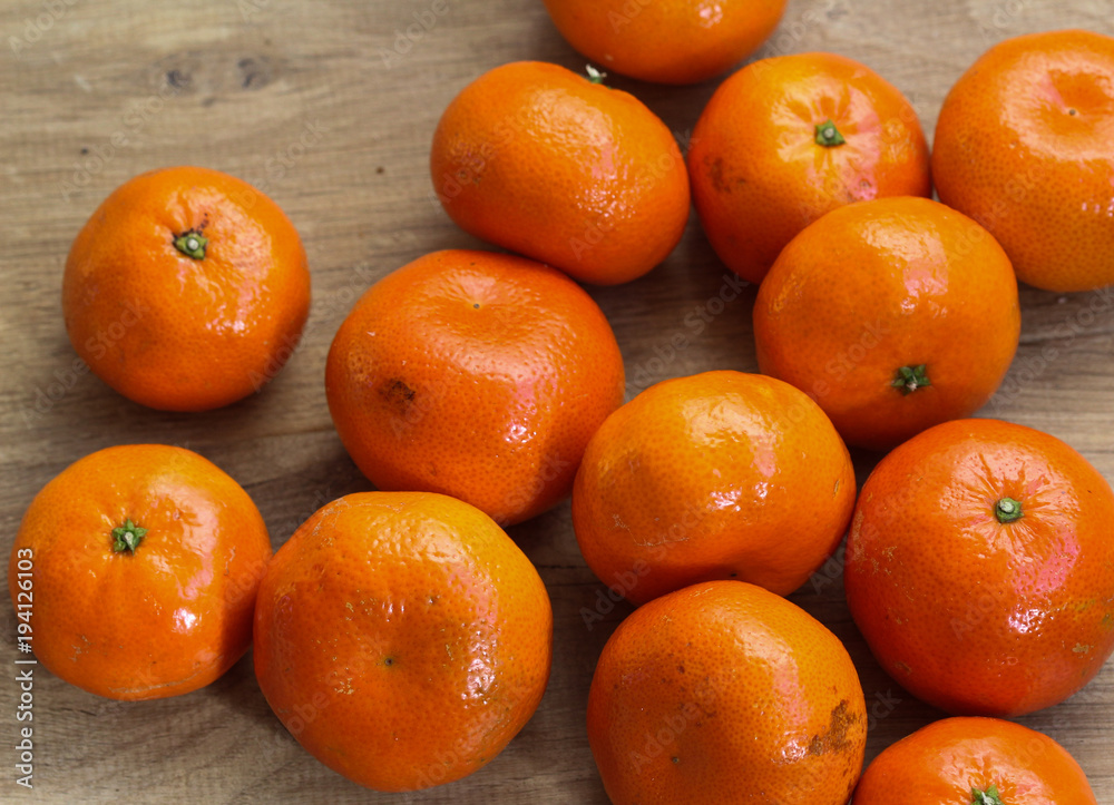 Bunch of fresh Mandarin orange, tangerine citrus fruit on wooden background Bunch of fresh Mandarin orange, tangerine citrus fruit on wooden background