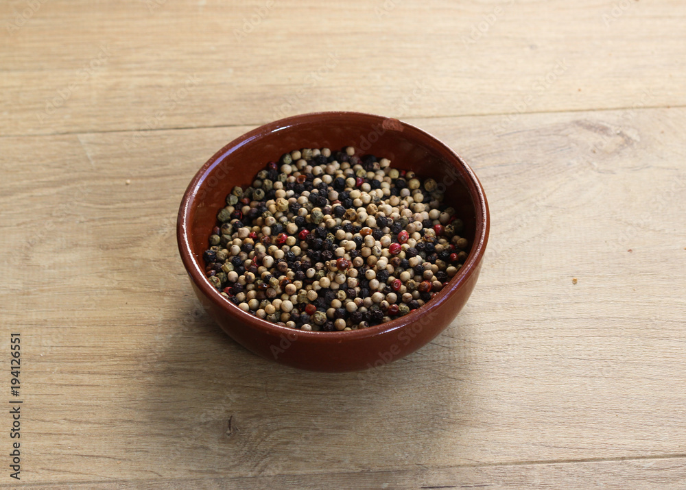 Four different season of peppers in stone bowl on wooden background Four different season of peppers in stone bowl on wooden background