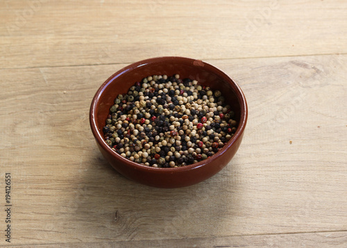 Four different season of peppers in stone bowl on wooden background