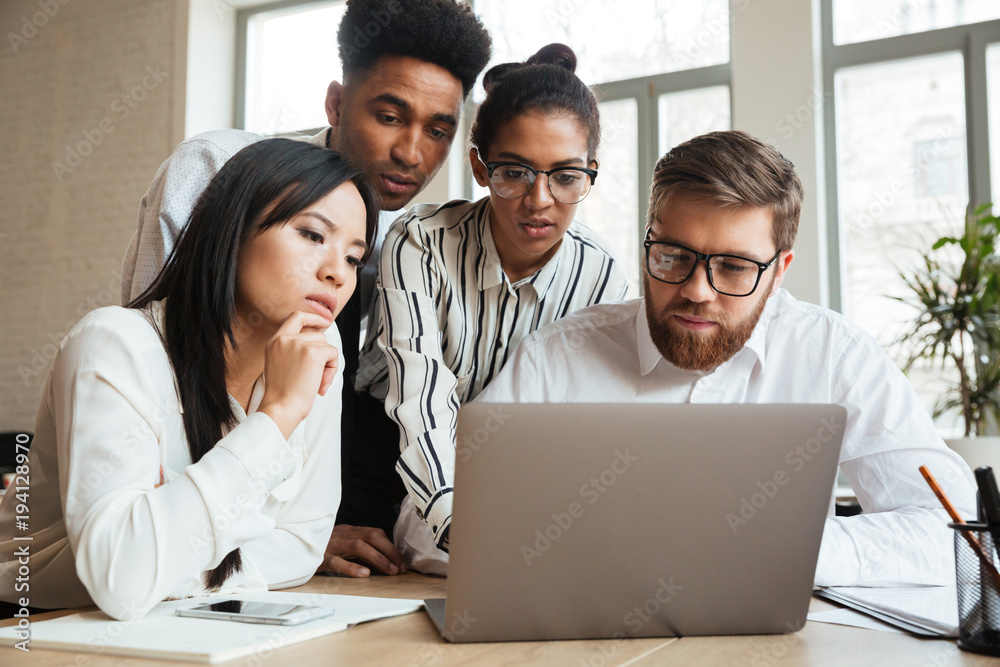 Concentrated serious young business colleagues using laptop computer. Concentrated serious young business colleagues using laptop computer.