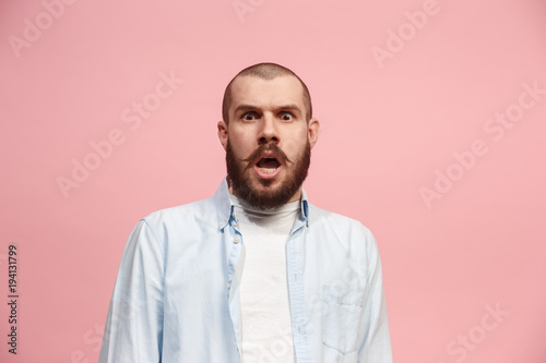 The young attractive man looking suprised isolated on pink