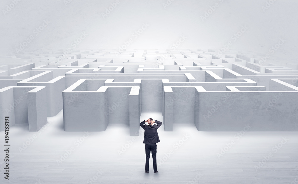 Businessman choosing between entrances at the edge of a maze Businessman choosing between entrances at the edge of a maze