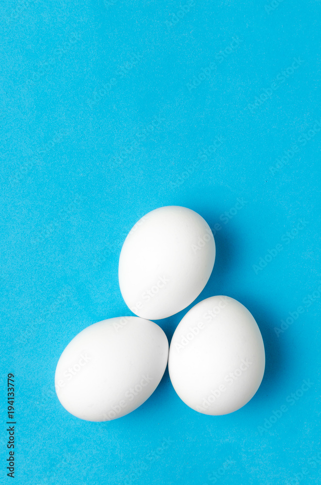White chicken eggs on blue background. White chicken eggs on blue background.