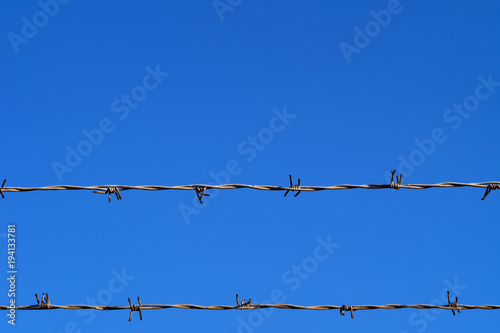 Double barbed wire fence against clear blue sky with copy space