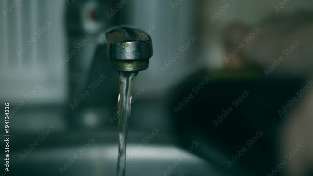 Water flows from the tap, the girl washes the dishes Water flows from the tap, the girl washes the dishes