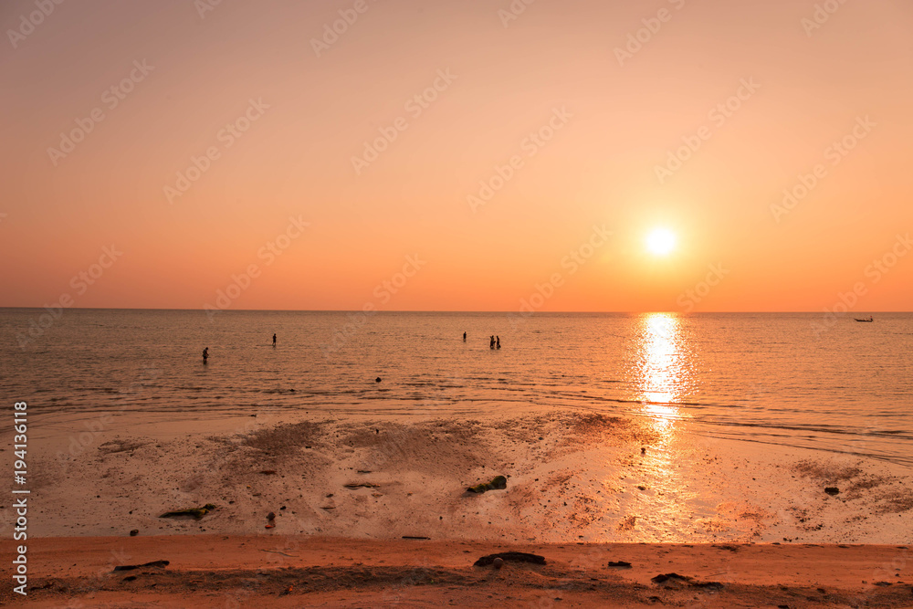 Silhouette of fishermen in the sea at sunset, orange sky.