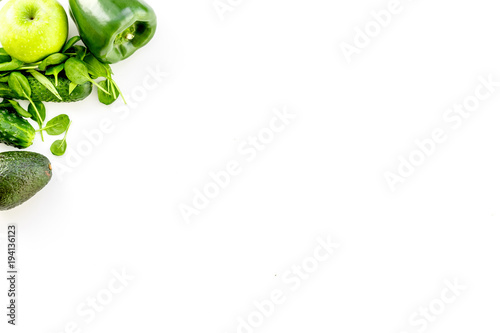 Green vegetables background. Shiny bell pepper, cucumber, arugula salad, avocado and fresh apple on white background top view copy space
