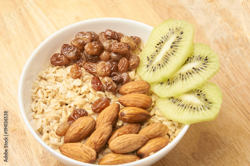 Neutral background. Oatmeal with kiwi raisins and almonds
