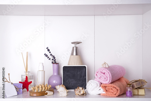 towels in a wooden tray with aroma chopsticks, candles, seashells, massage washcloths and a bottle with a dispenser