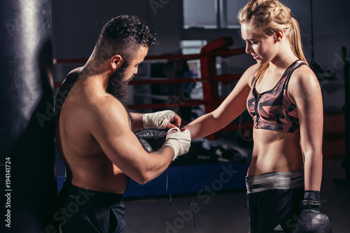 coach puts on boxing gloves young athlete before fight photo