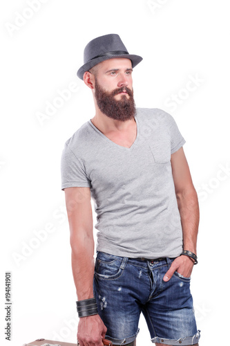 Portrait of handsome bearded man in hat standing , isolated on grey background