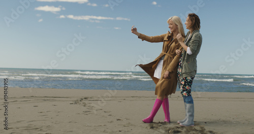 Girls having time and taking selfie on a beach © .shock