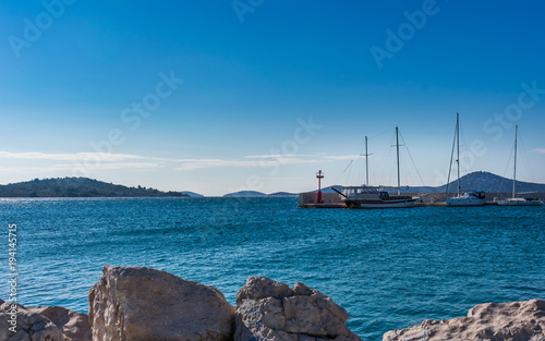 Beautiful landscape or seascape view of sailing boats moored at a pier or dock with islands in the background, Croatian coast
