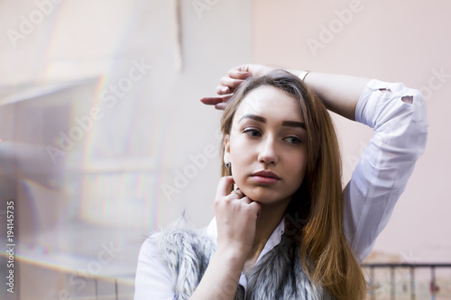 Pretty brunette model in white shirt posing in the entrance of the apartment building