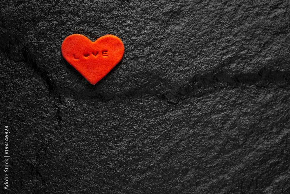 Red heart written love words placed on black stone floor Red heart written love words placed on black stone floor