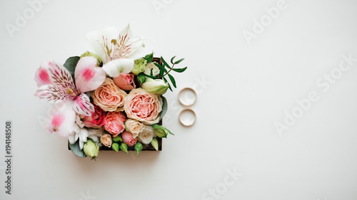 Two golden wedding rings arranged near beautiful and cute flower composition in a little box © fesenko