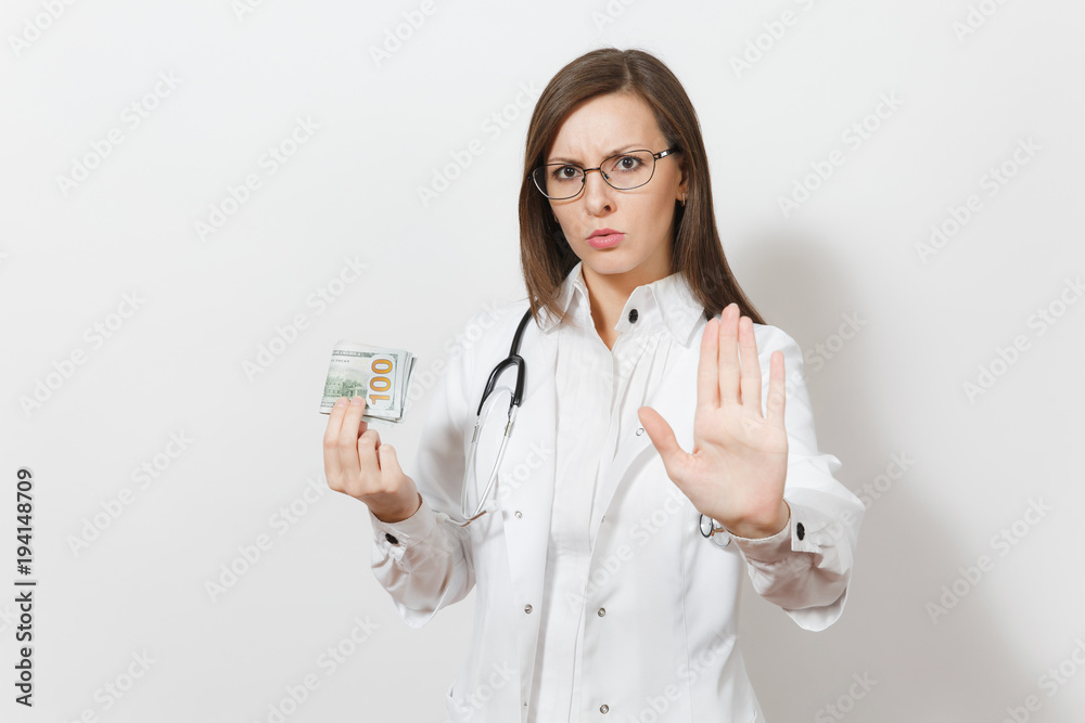 Doctor woman showing stop gesture with palm isolated on white background. Female doctor in medical gown with stethoscope holding cash money banknotes, pack of dollars. Healthcare personnel concept. Doctor woman showing stop gesture with palm isolated on white background. Female doctor in medical gown with stethoscope holding cash money banknotes, pack of dollars. Healthcare personnel concept.