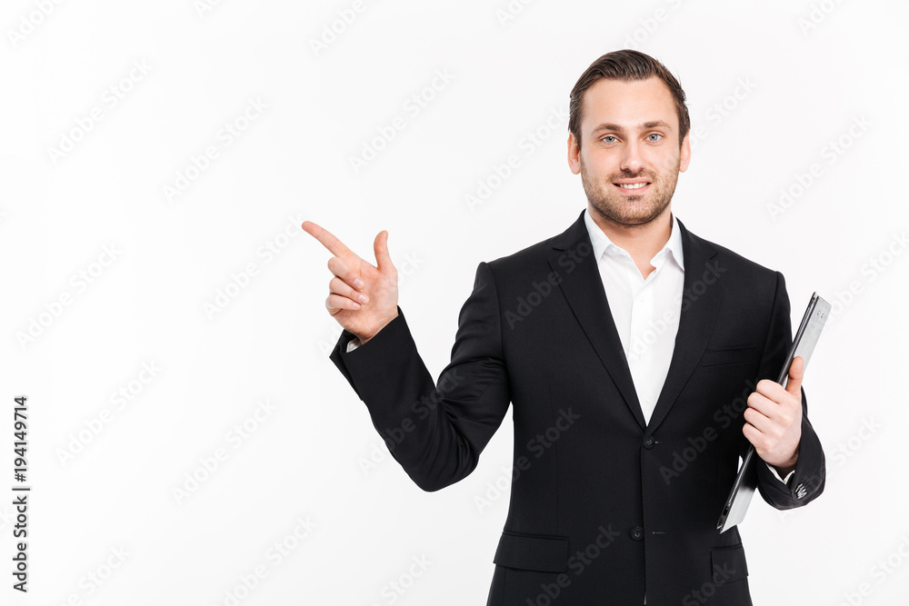 Photo of successful entrepreneur wearing business suit pointing finger aside and posing with documents in hand, isolated over white background copy space Photo of successful entrepreneur wearing business suit pointing finger aside and posing with documents in hand, isolated over white background copy space