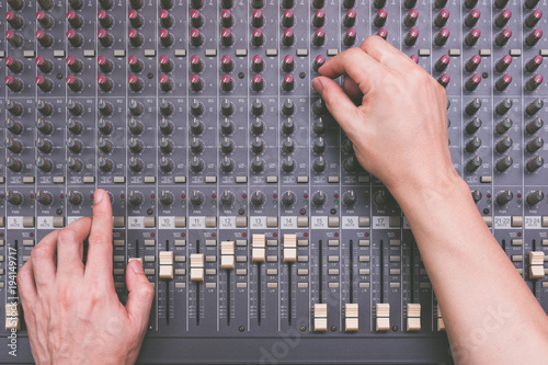 male sound engineer hands working on audio mixing console