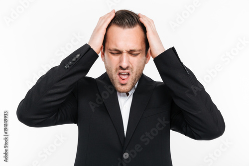 Horizontal portrait of tense man in suit grabbing his head being stressed and thinking about solution of problem, isolated over white background