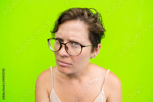 Portrait of a Woman in Glasses with a look at the camera and an Unhappy Face. Question and discontent. photo