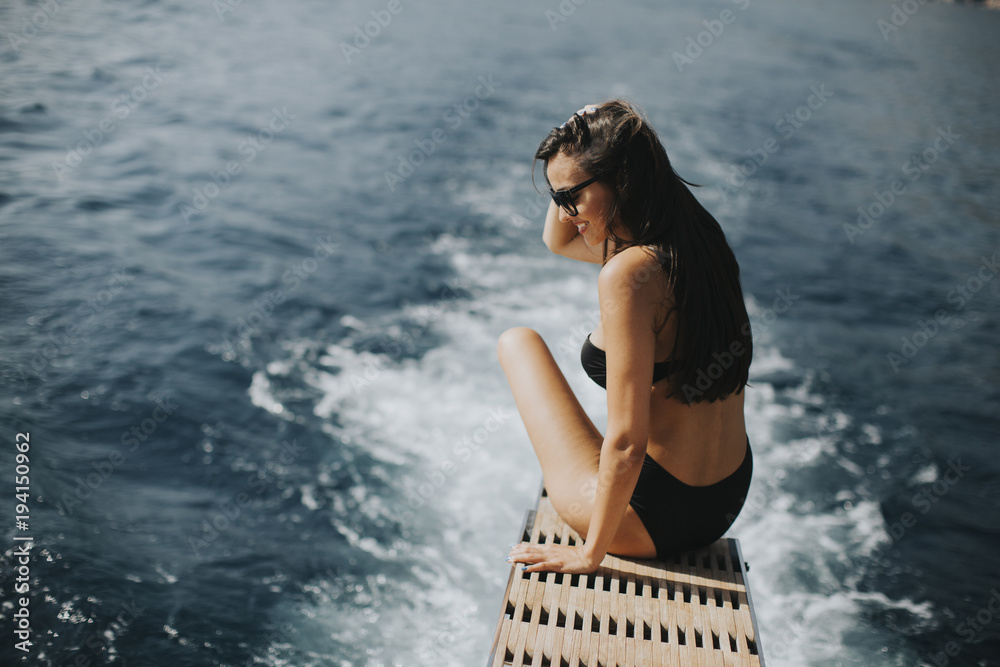 Fototapeta premium Pretty woman relaxing on the yacht on sea at sunny day