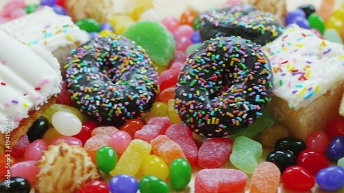 Overhead panning shot of dessert table with cake, donuts, candy and junk food.