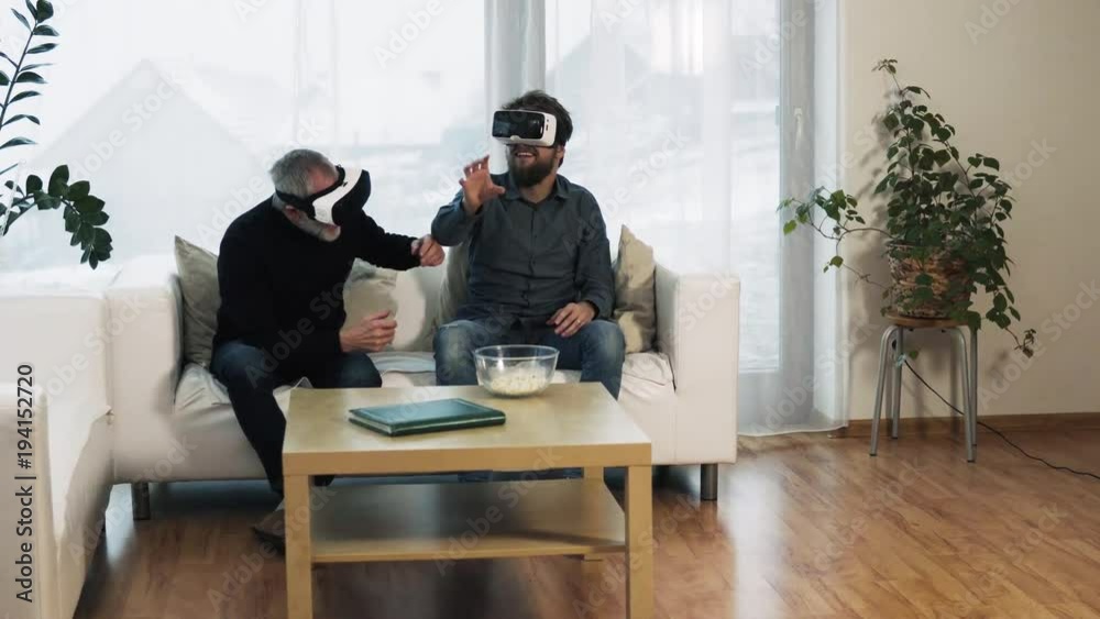 Hipster son and his senior father with VR goggles at home. Hipster son and his senior father with VR goggles at home.