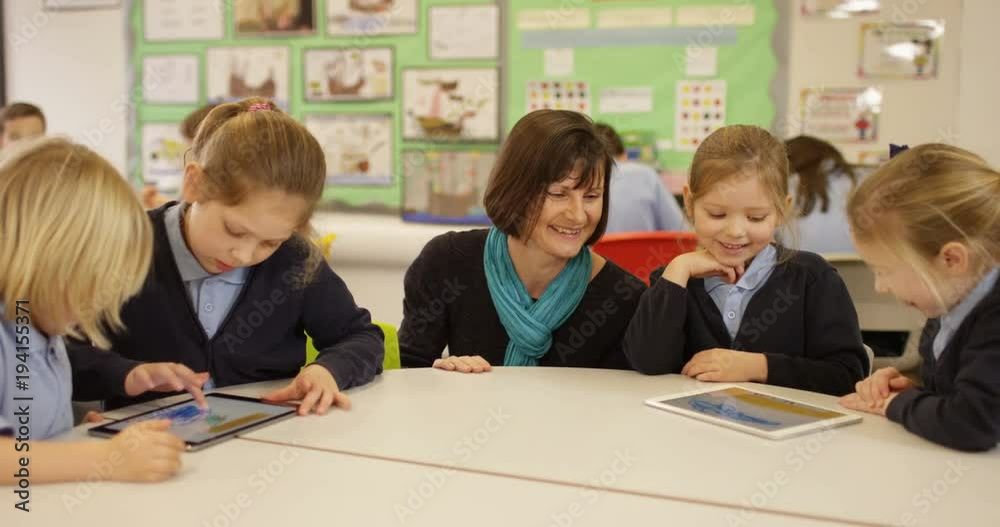 4k, Elementary school teacher with her pupils in classroom using a digital touchscreen tablet. Slow motion. 4k, Elementary school teacher with her pupils in classroom using a digital touchscreen tablet. Slow motion.