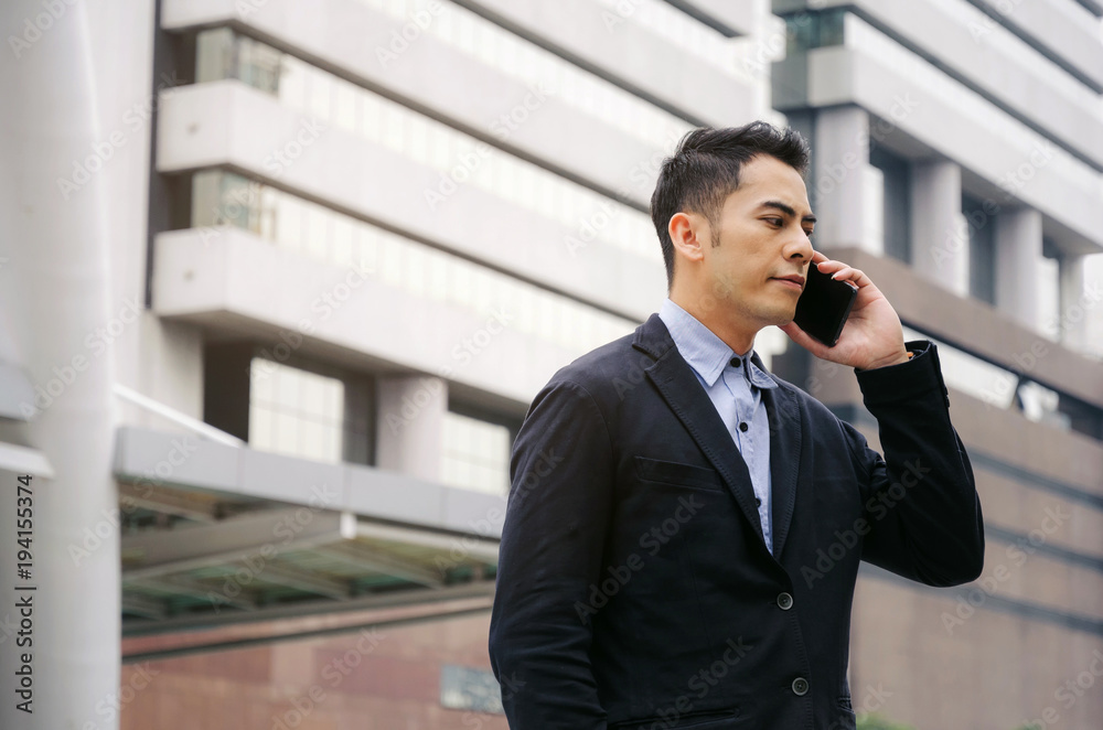 young smart asian business man wearing modern black suit making phone call with mobile smart phone in building city background, internet network connection, technology communication, financial concept young smart asian business man wearing modern black suit making phone call with mobile smart phone in building city background, internet network connection, technology communication, financial concept