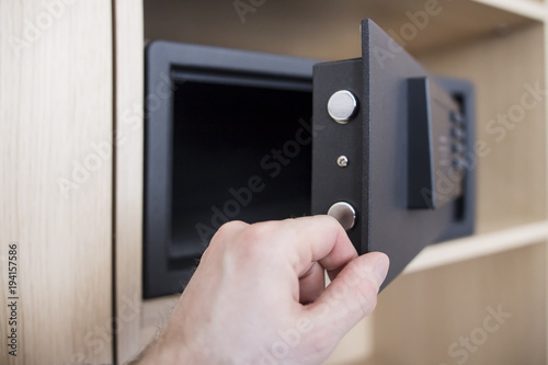 Open safe door with electronic lock close up. Keep money and jewelry at home. man's hand and safe in the apartment.