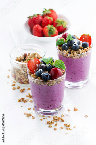 Blueberry dessert with granola in glass on a white background, vertical