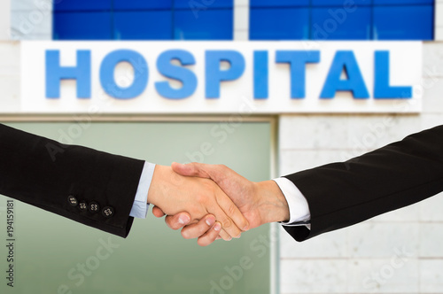 Cropped shot of a doctor shaking the hand of a patient next hospital building photo