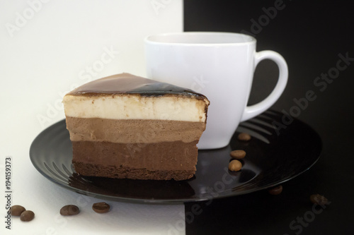 Cake on a black plate and coffee in a white Cup.