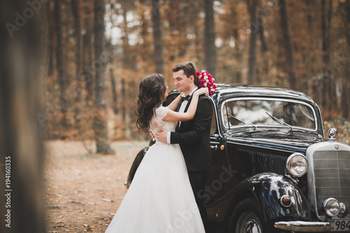 Just married happy couple in the retro car on their wedding © olegparylyak