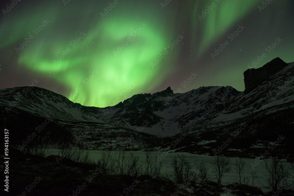 Bright green Northern Light (Aurora Borealis) lighting up the dark skies above the mountains, Tromsø, Norway Bright green Northern Light (Aurora Borealis) lighting up the dark skies above the mountains, Tromsø, Norway