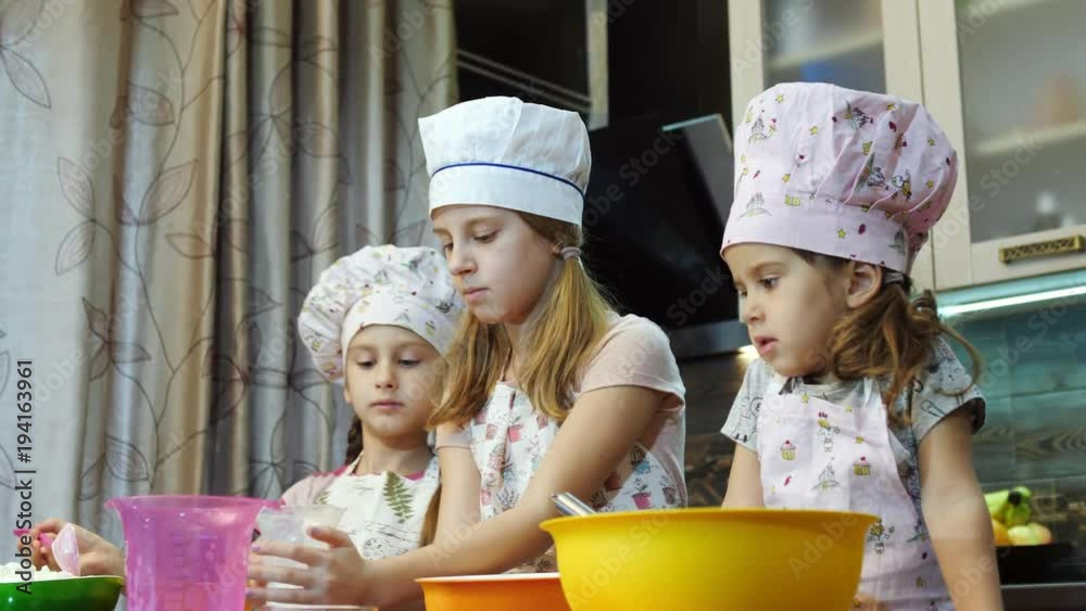 Three adorable little cooks mixing dough together Three adorable little cooks mixing dough together