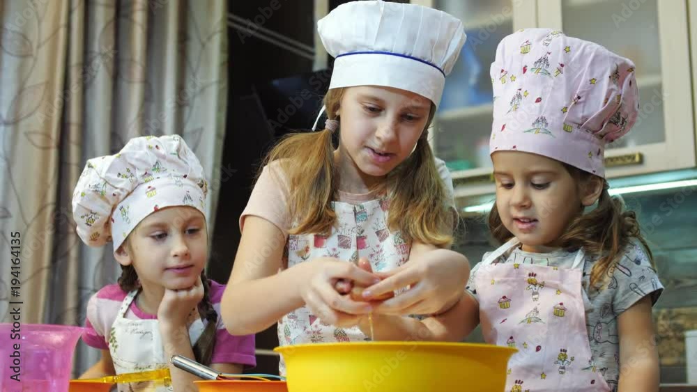 Happy kids having fun in the kitchen.Children cracking eggs into a bowl. Happy kids having fun in the kitchen.Children cracking eggs into a bowl.