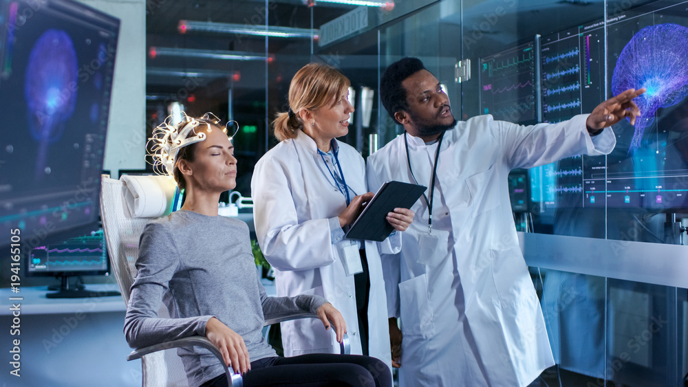 Woman Wearing Brainwave Scanning Headset Sits in a Chair while Two ...