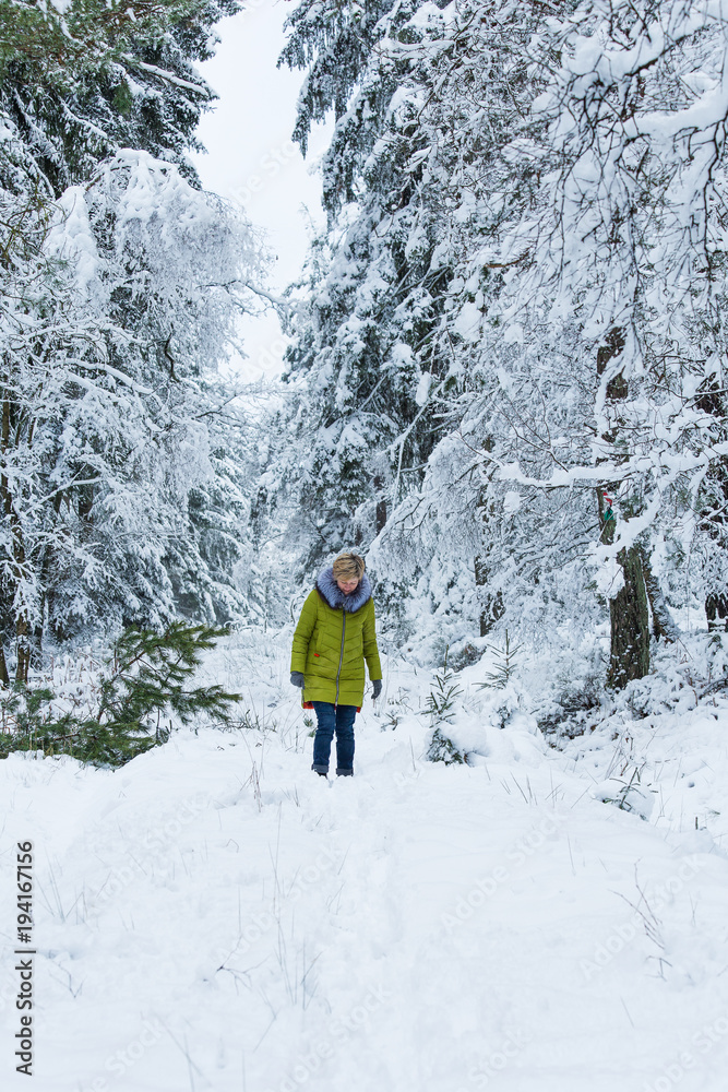 A young woman is walking through the winter forest