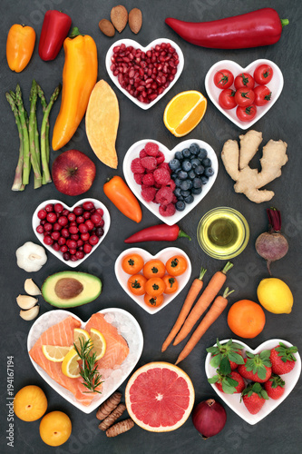 Food to maintain a healthy heart concept with salmon, vegetables, fruit, spice, nuts on slate background. Super foods high in antioxidants, vitamins, minerals, omega 3 fatty acids and anthocyanins. 