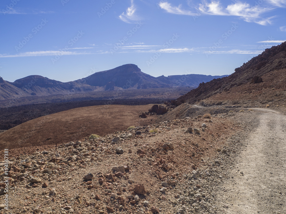 curved footpath road to volcano pico del teide with desert volcanic landscape orange and purple mountain, clear blue sky background