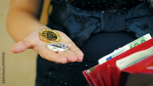 Close-up of a girl holding in her hand two cryptocoins - Bitcoin and Lightcoin in slow motion photo