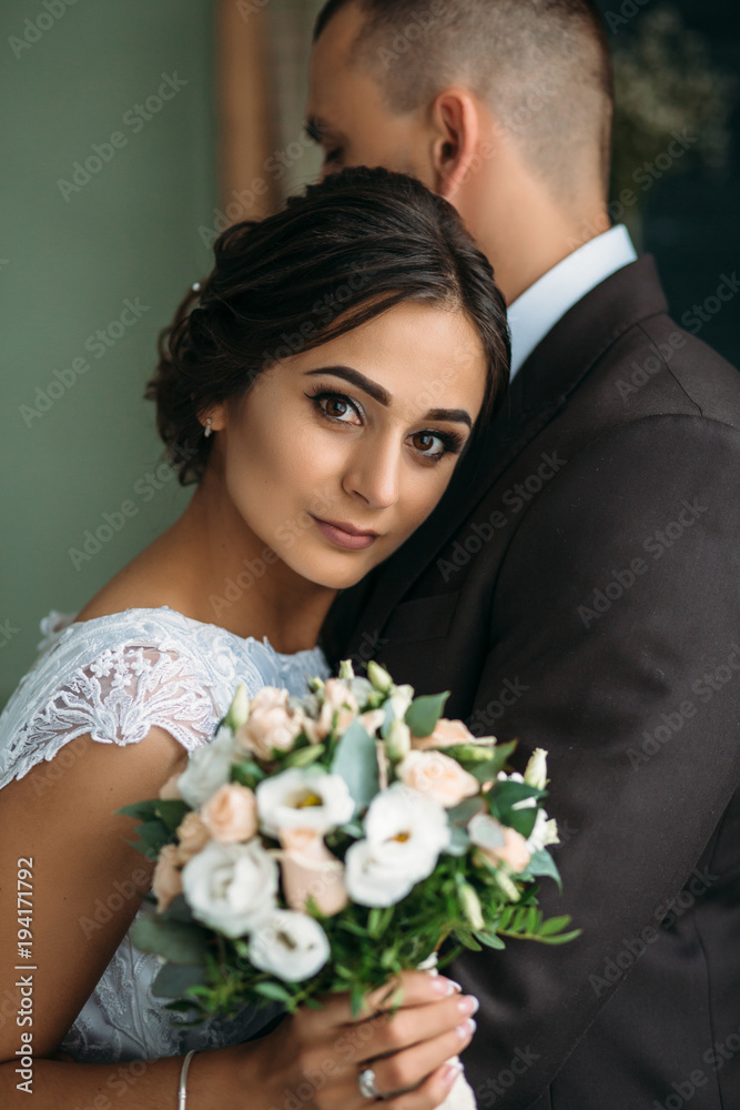 Bride leans to groom's shoulder tender standing in the room Bride leans to groom's shoulder tender standing in the room